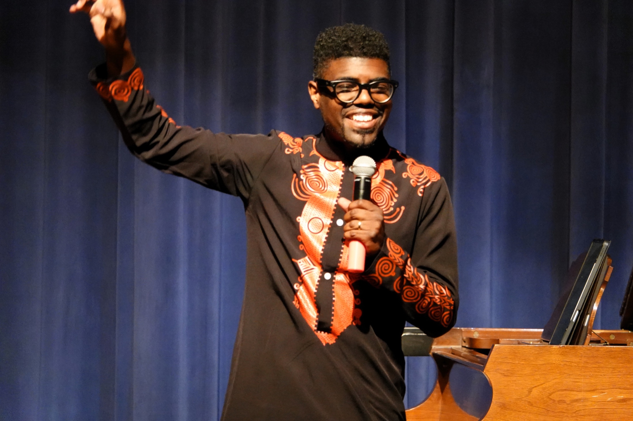 Kyle P. Walker smiling while speaking with students during an auditorium program