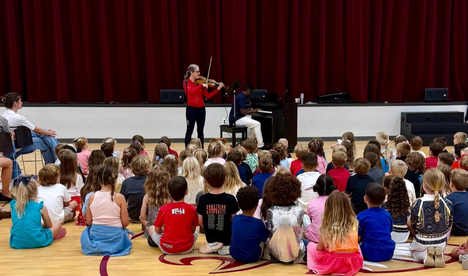 Students gathered for an interactive performance with piano and violin